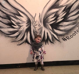 Toddler standing in front of wings mural